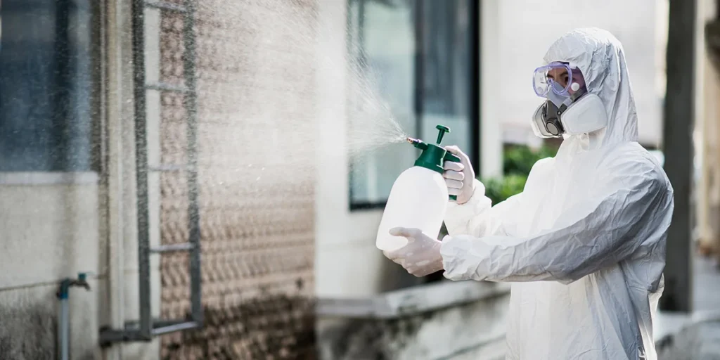 Disinfection specialist in PPE suit performing spray public decontamination