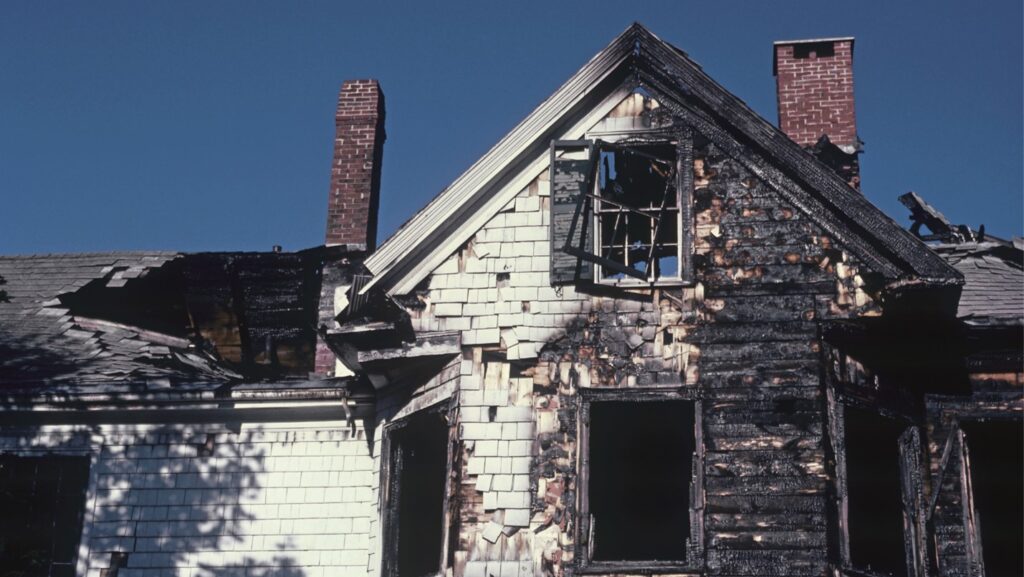 A house that has been badly damaged by fire, its face is charred black.