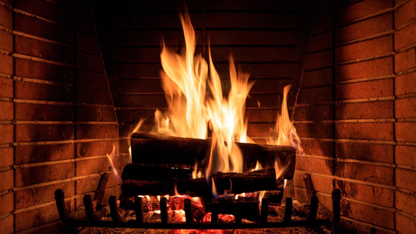 A roaring fireplace with logs resting on an elevated grate.