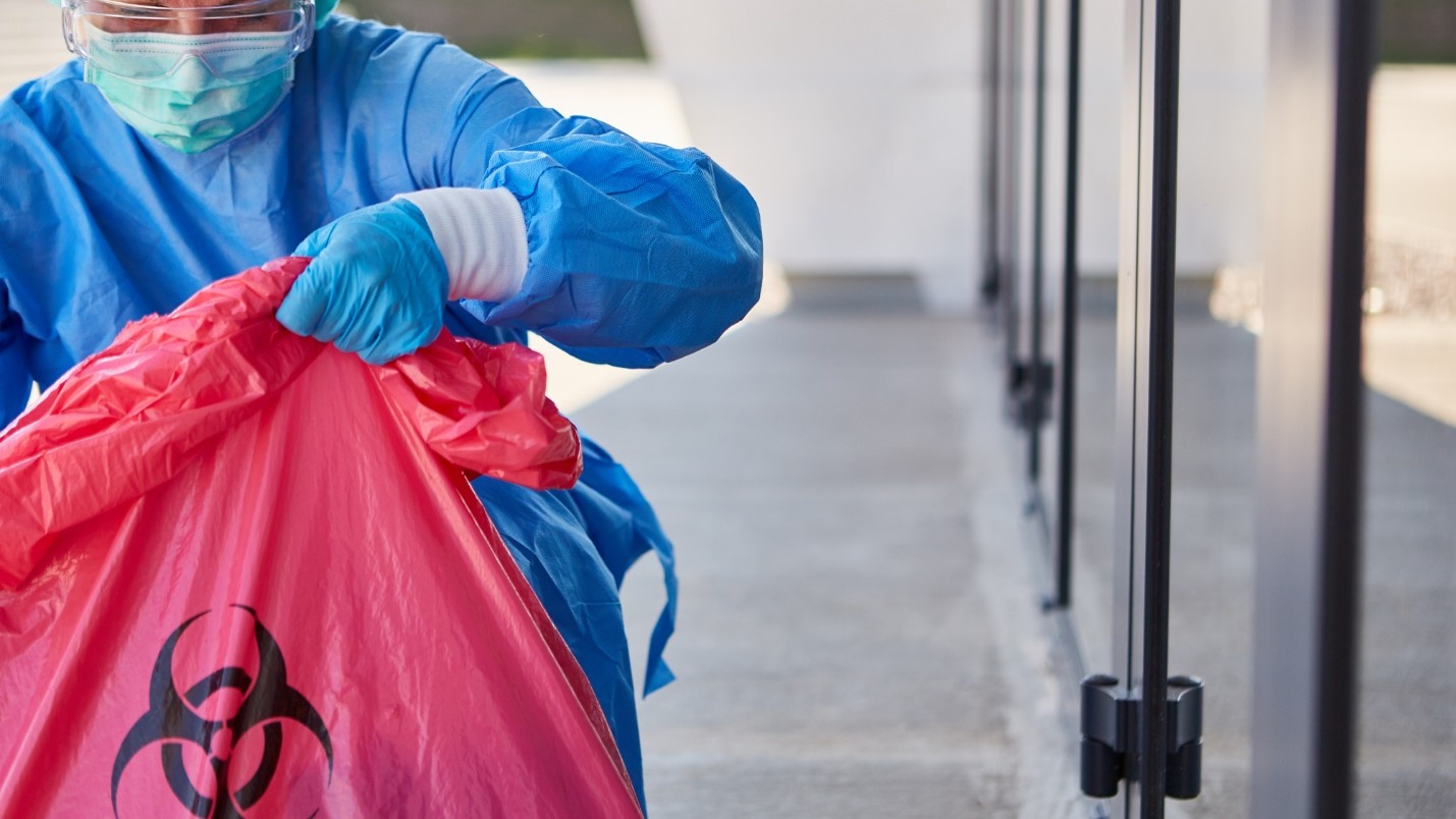 A biohazard cleanup specialist uses a large red bag with the biohazard symbol on it.