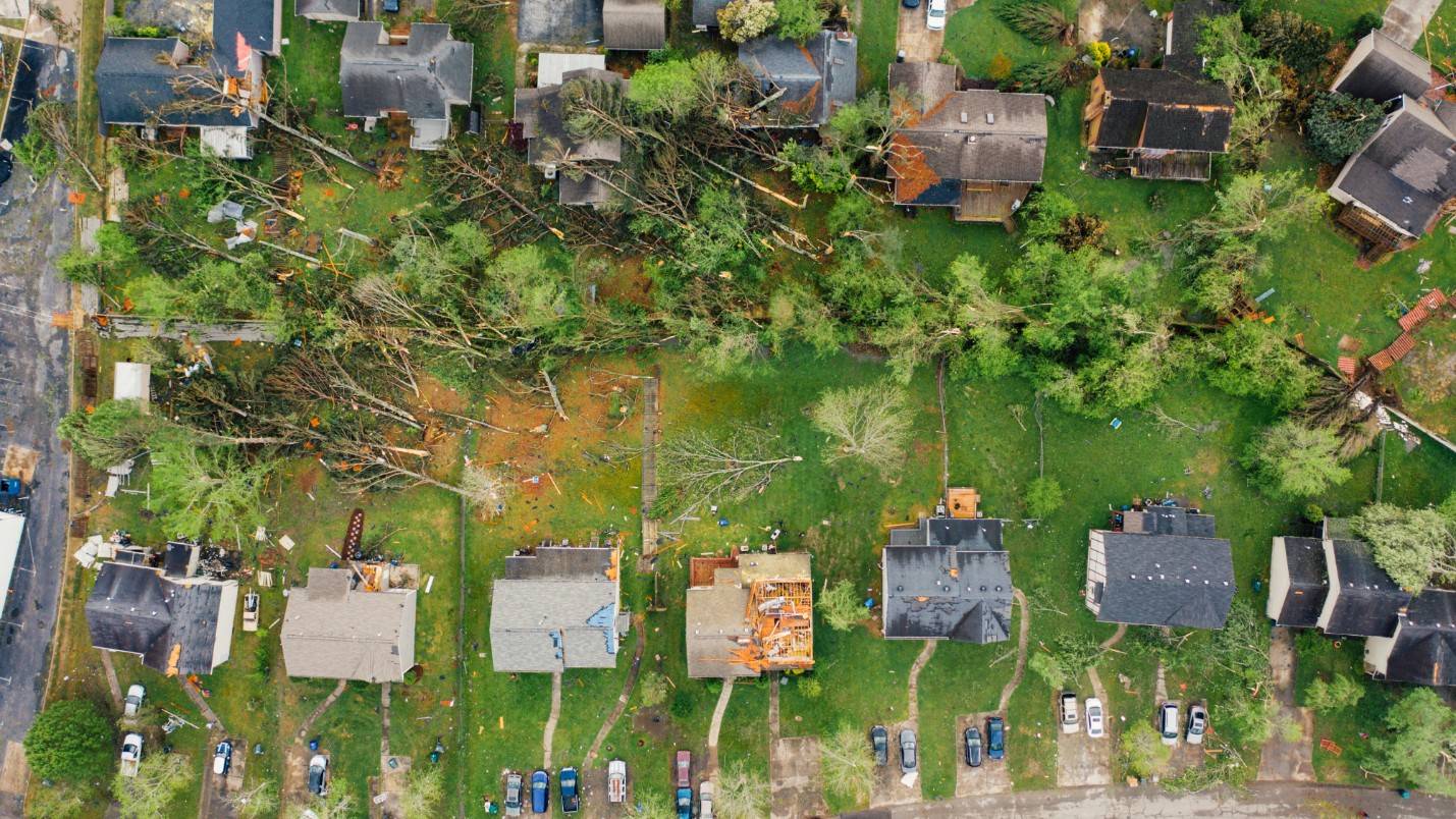 A birds-eye-view of a neighborhood with downed trees after a major storm.