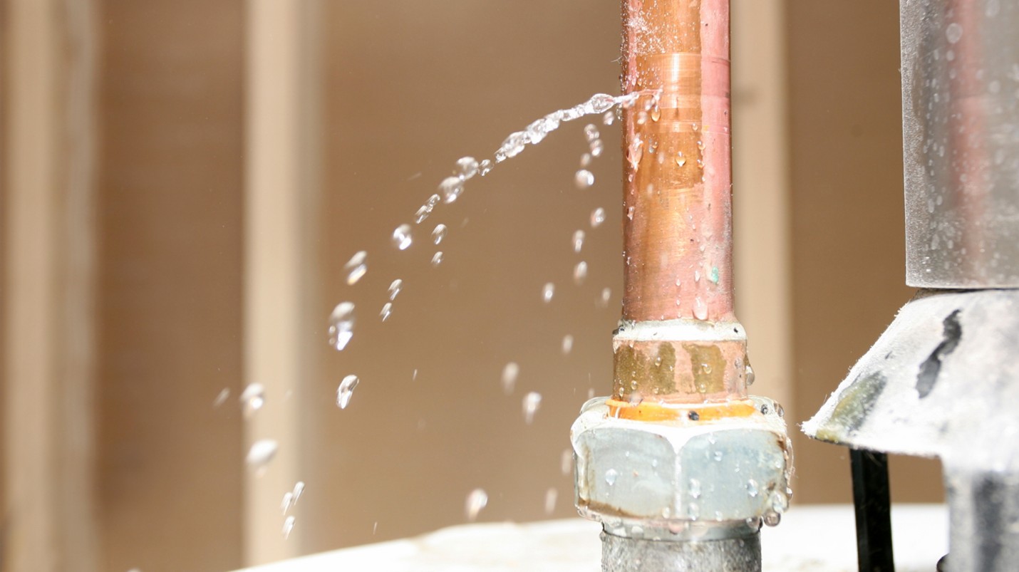 A copper pipe leaks out water into a home.