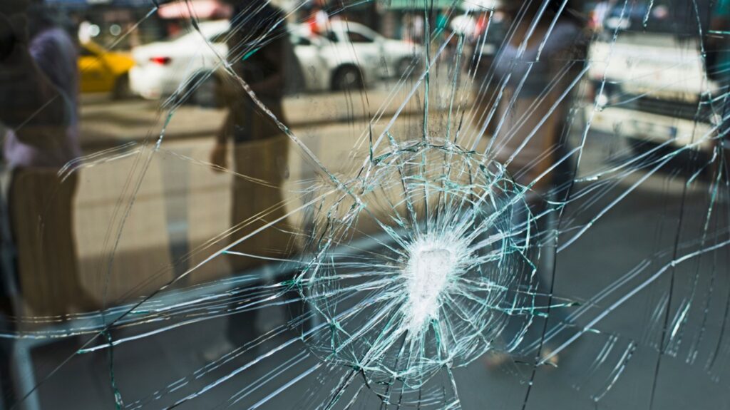 The broken window of a commercial building reflects the town street.