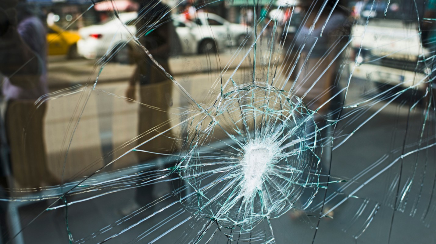 The broken window of a commercial building reflects the town street.